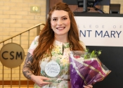College of Saint Mary student Alexis Winter wears a floral dress and poses with a bouquet of flowers and her Heart of the Walking Woman award.